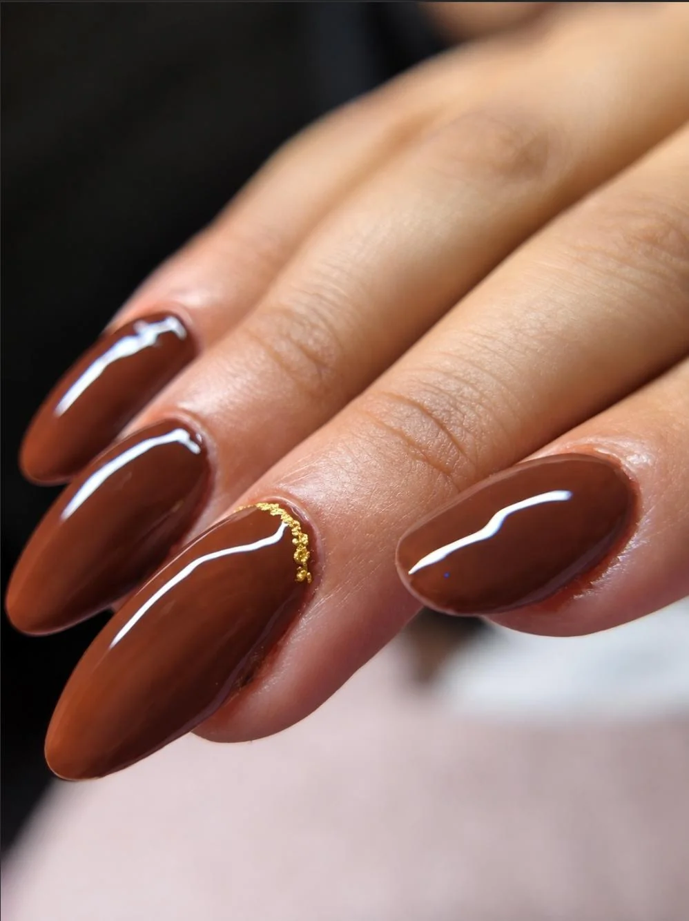 Esmaltação em gel marrom com detalhe em brilho dourado na cutícula